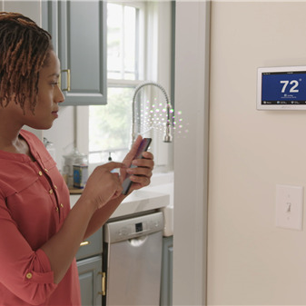 A Woman Adjusts Thermostat.